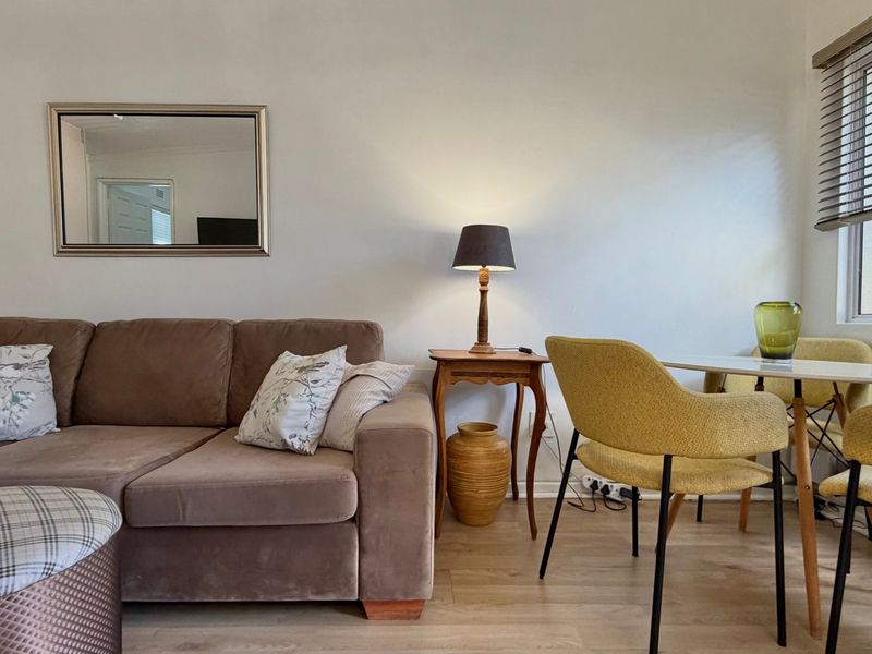 A living area featuring light-toned laminate flooring and window blinds, providing a neutral base for interior design.