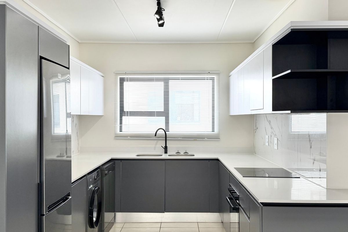 Modern U-shaped kitchen featuring sleek grey and white cabinetry, quartz countertops, marble-look splashbacks, and integrated appliances in a clean, contemporary finish.