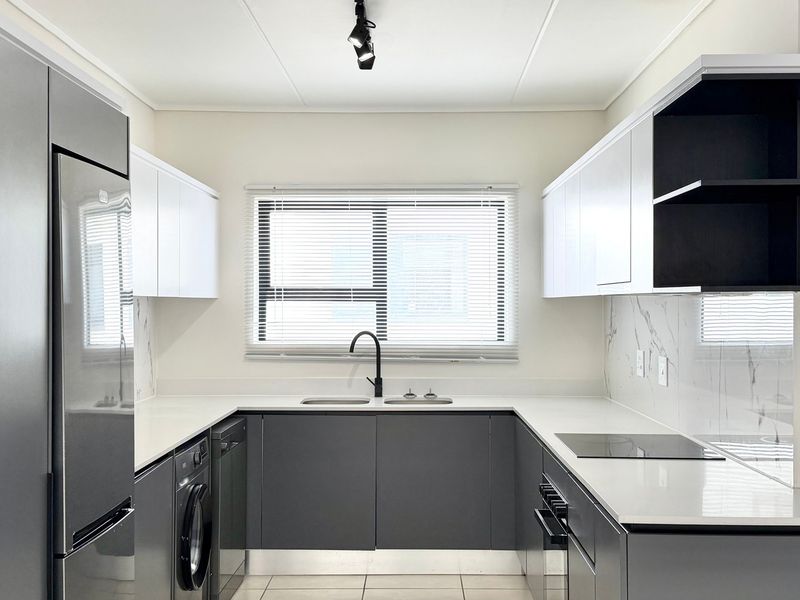 Modern U-shaped kitchen featuring sleek grey and white cabinetry, quartz countertops, marble-look splashbacks, and integrated appliances in a clean, contemporary finish.