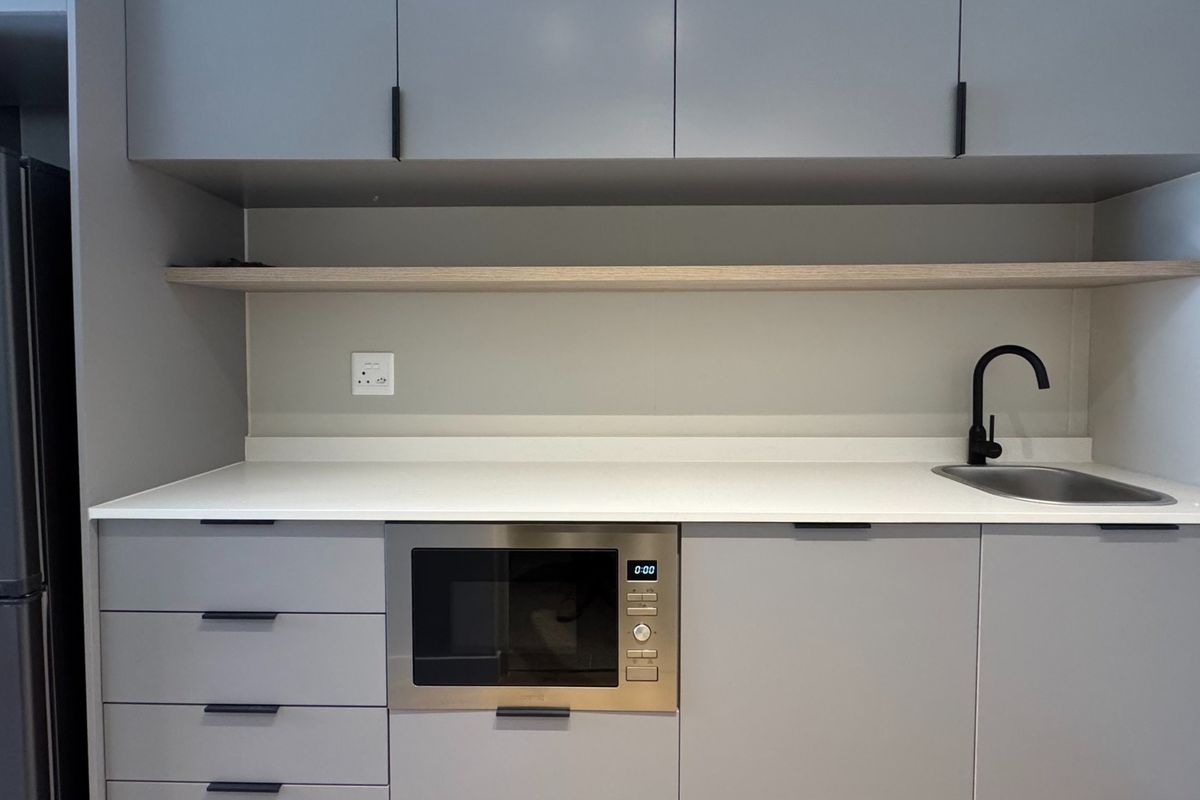 Modern kitchen featuring sleek grey cabinetry, white quartz countertops, an undermount sink with a black mixer tap, and a built-in microwave.