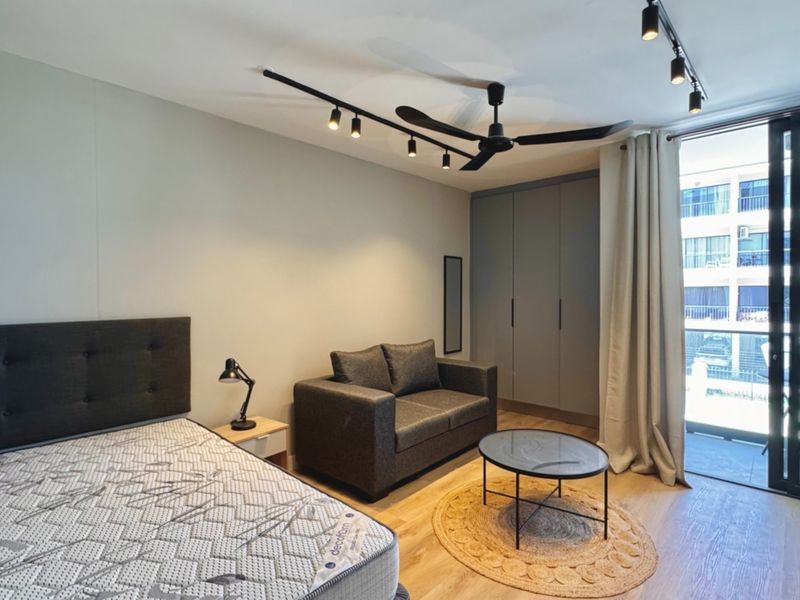Modern bedroom featuring built-in cupboards, track lighting, a ceiling fan, and direct access to a private balcony through sliding glass doors.