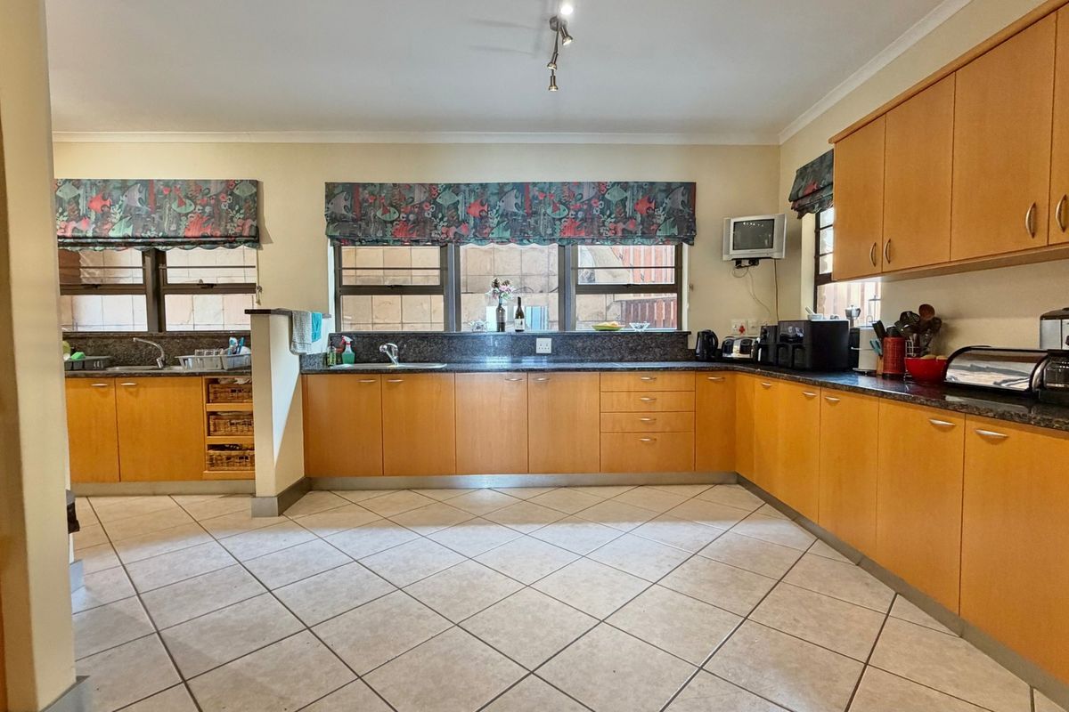Spacious kitchen featuring extensive laminate cabinetry, granite countertops, tiled flooring, and a functional layout with ample storage and workspace.