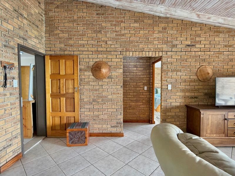 A living room featuring exposed brick walls, vaulted timber ceilings, and tiled flooring, providing a rustic aesthetic with potential for modern updates.