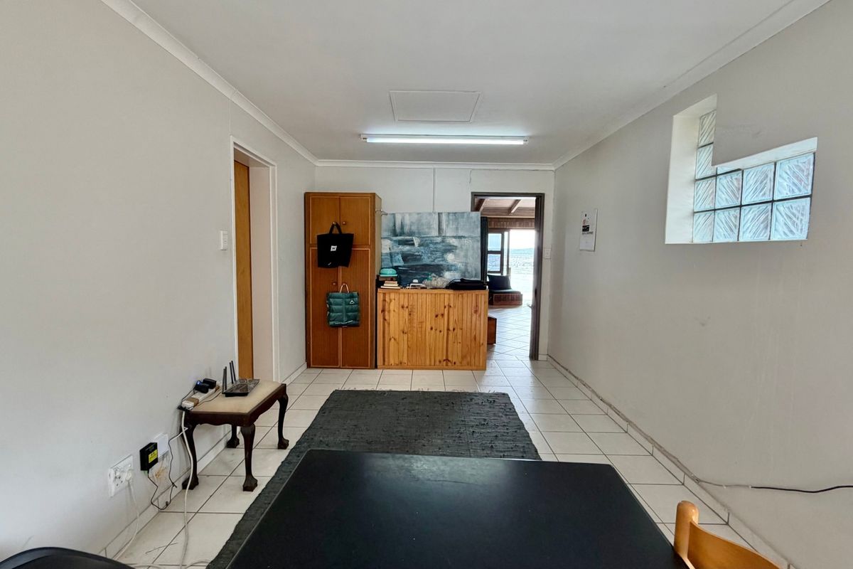 A functional living area featuring tiled flooring, a unique glass block window, and direct access to an adjoining space.