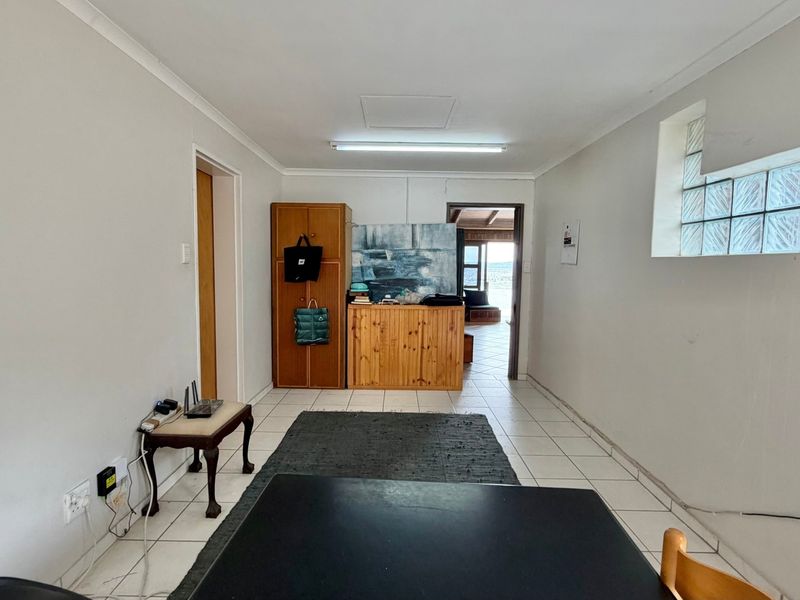 A functional living area featuring tiled flooring, a unique glass block window, and direct access to an adjoining space.