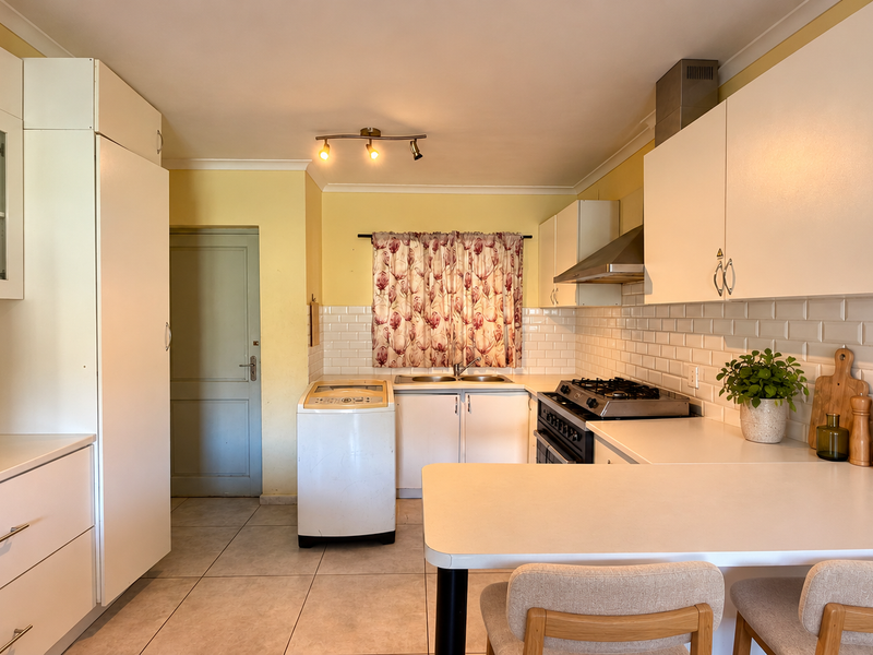 A functional kitchen featuring white cabinetry, a subway tile backsplash, gas hob with extractor, and a convenient breakfast counter for casual dining.