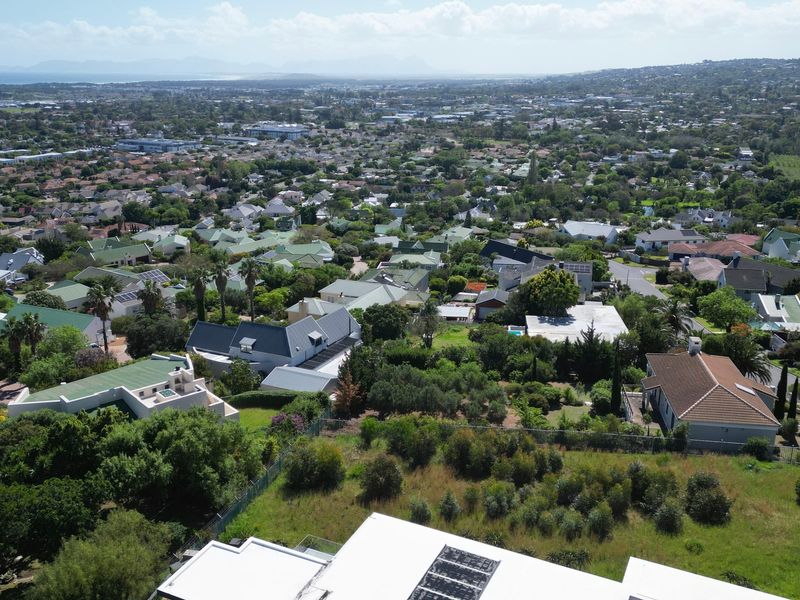 An aerial view of a residential neighborhood showing surrounding properties, mature trees, and established landscaping.