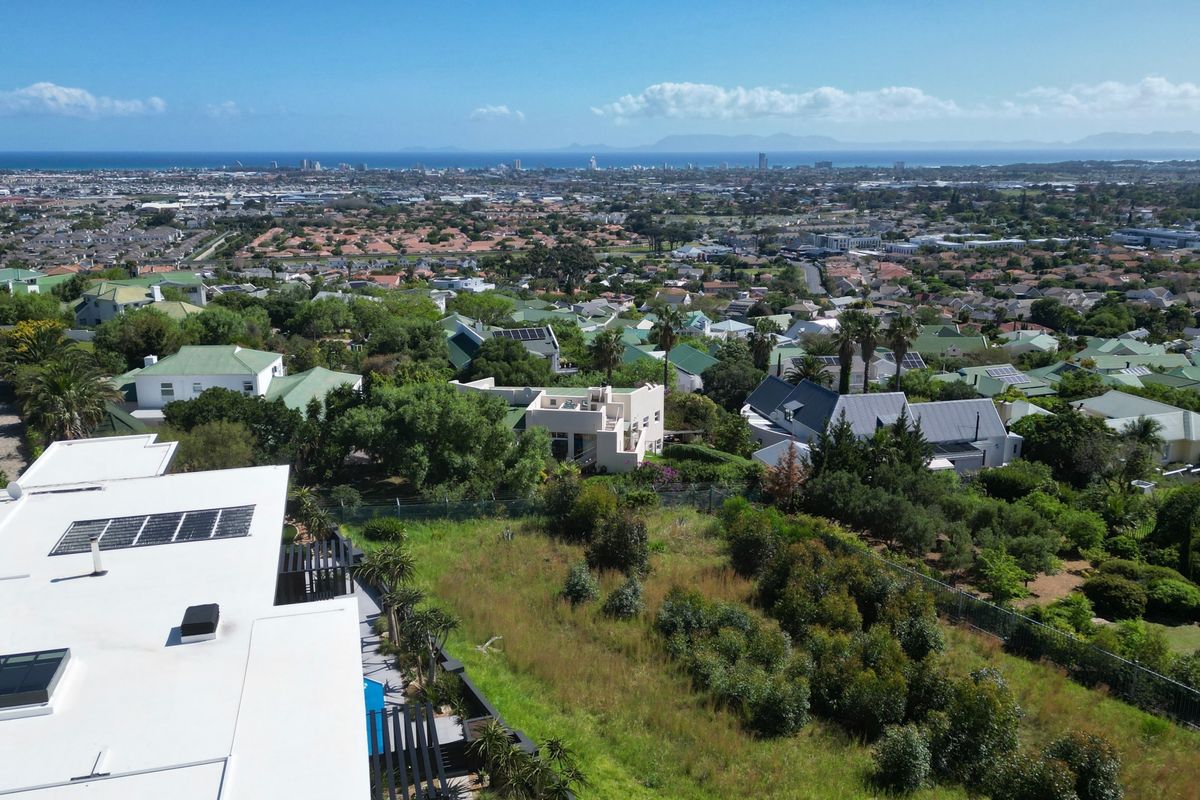 An elevated aerial view showcasing the residential property, surrounding neighborhood, and distant coastal landscape.