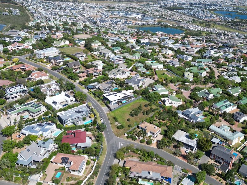 An aerial view of a residential estate featuring established homes, landscaped gardens, and surrounding neighborhood infrastructure.
