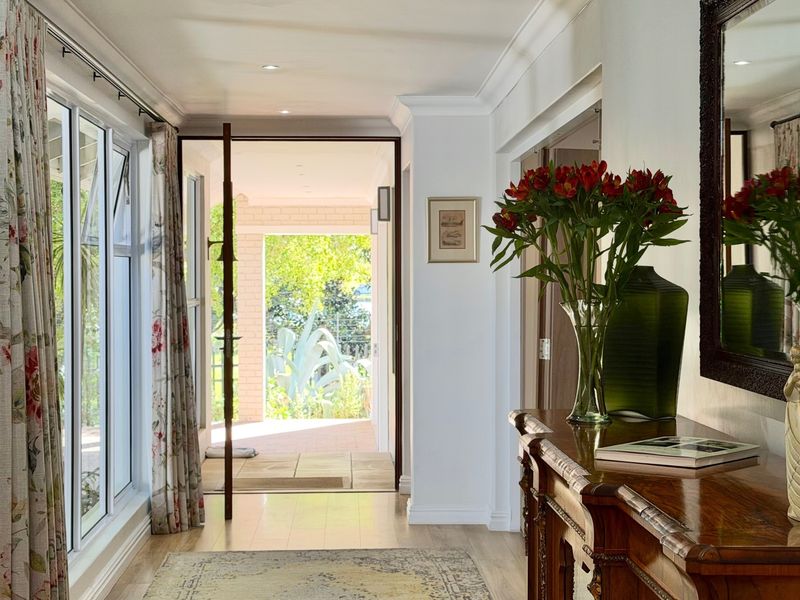 Bright and welcoming entrance hall featuring laminate flooring, recessed downlights, and large sliding glass doors providing direct access to the outdoor patio area.