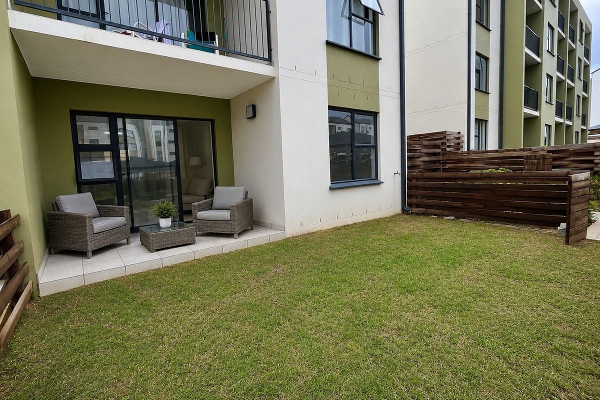 Ground floor apartment featuring a private tiled patio, small lawn area, and timber privacy fencing, with direct access to the living space.