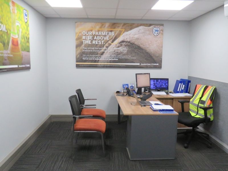 A professional office space featuring recessed ceiling lighting, a wall-mounted air conditioning unit, and dark carpeted flooring.