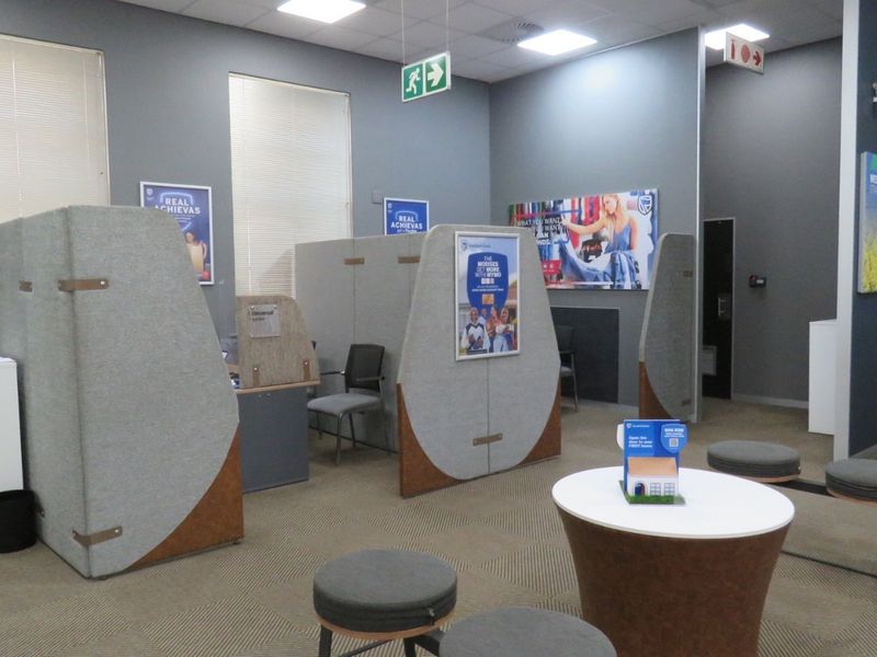 A professional office space featuring partitioned workstations, recessed ceiling lighting, and carpeted flooring, suitable for a business or banking environment.