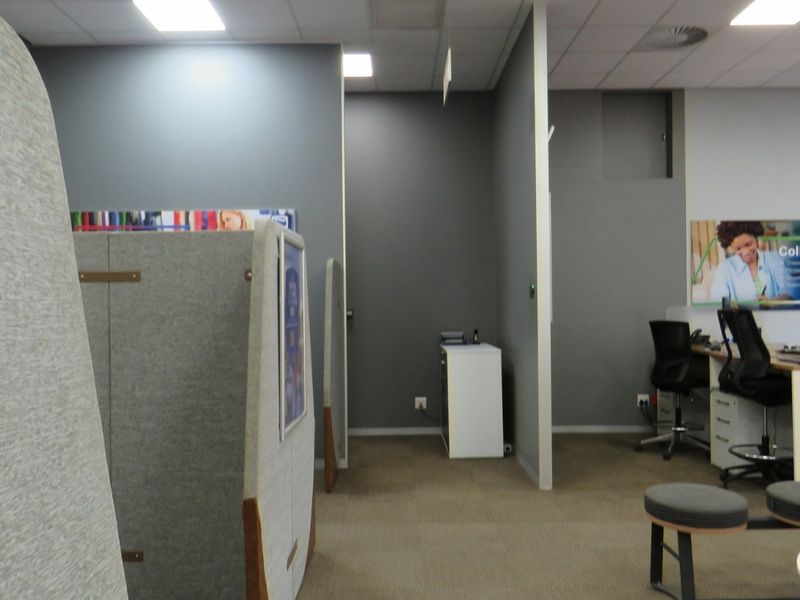 A functional office space featuring carpeted flooring, suspended ceilings with recessed lighting, and partitioned work areas.