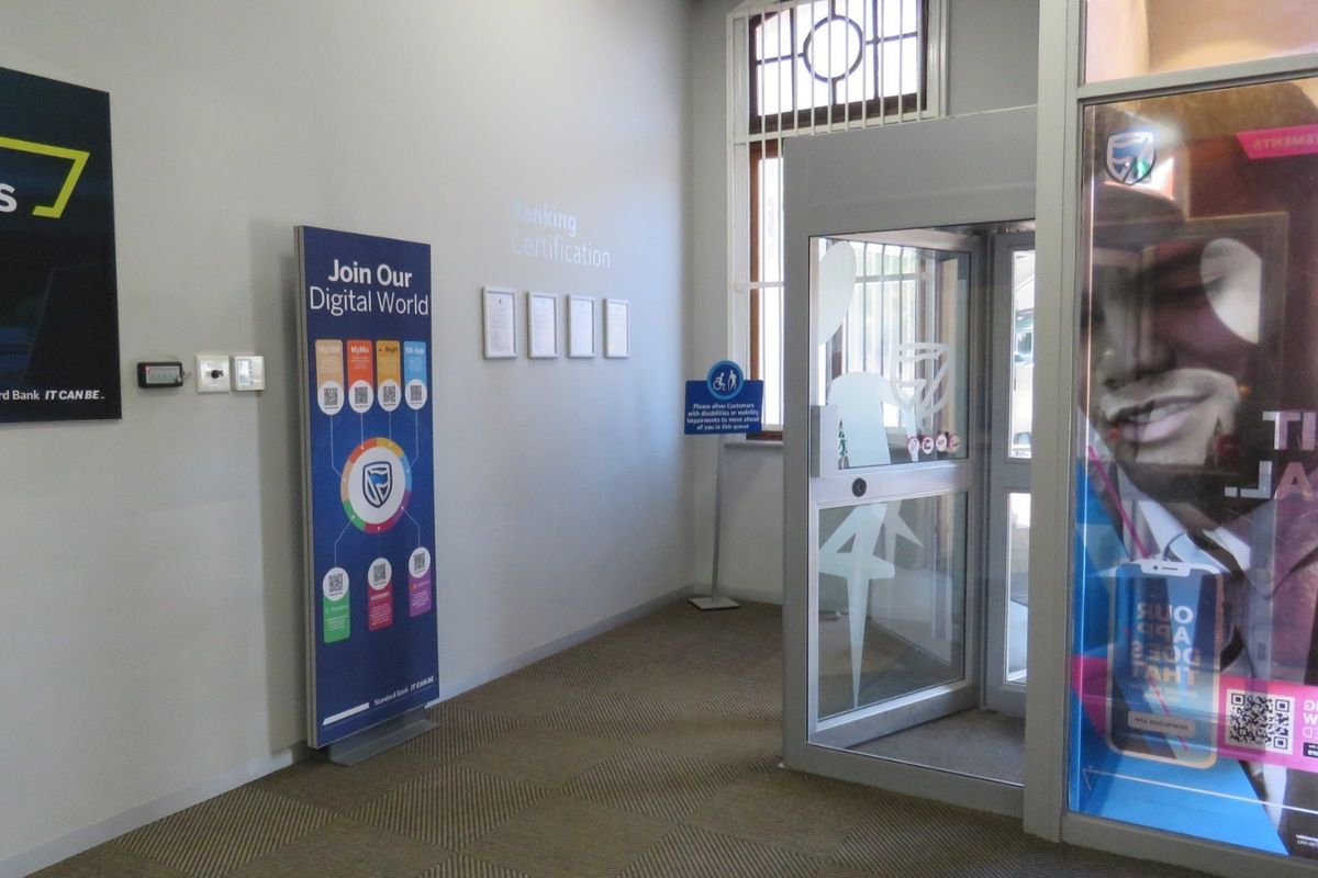 A clean and functional bank entrance area featuring a security revolving door, carpeted flooring, and professional signage.