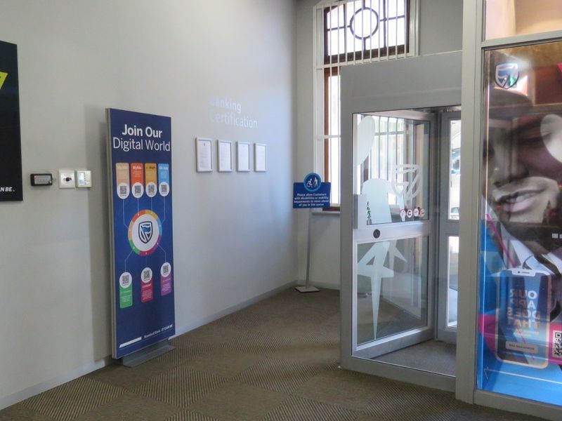 A clean and functional bank entrance area featuring a security revolving door, carpeted flooring, and professional signage.