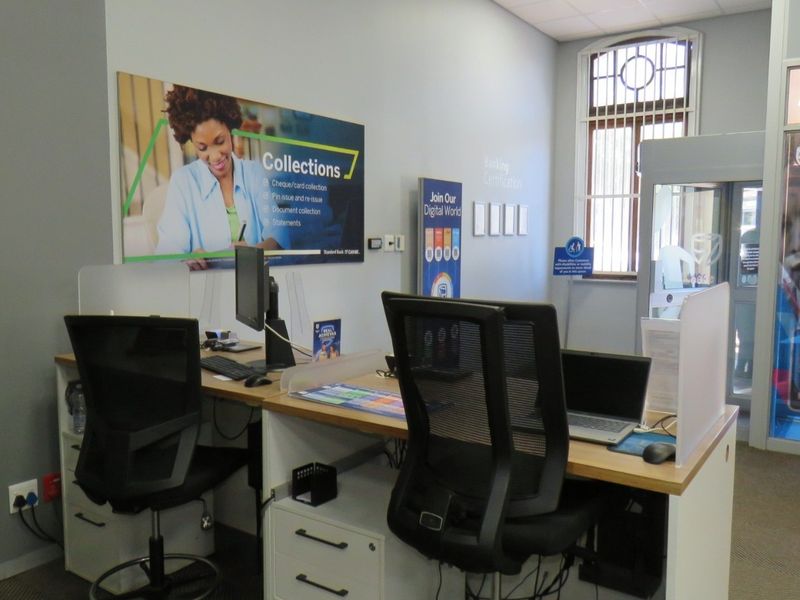 A functional bank office space featuring built-in workstations, security access control, and professional branding elements.