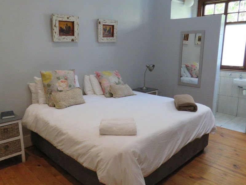 A bedroom featuring timber flooring and direct access to an en-suite bathroom area.