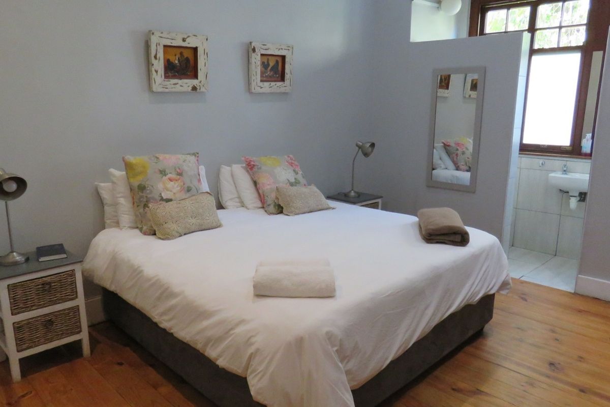 A bedroom featuring timber flooring and direct access to an en-suite bathroom area.