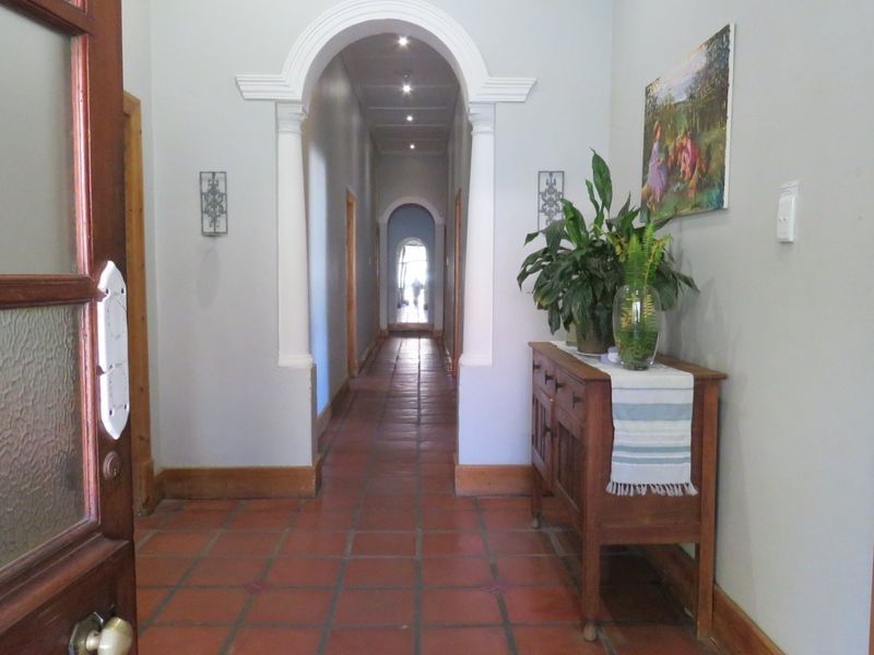 A welcoming entrance hallway featuring classic terracotta floor tiles, an elegant arched entryway with decorative columns, and recessed ceiling lighting.