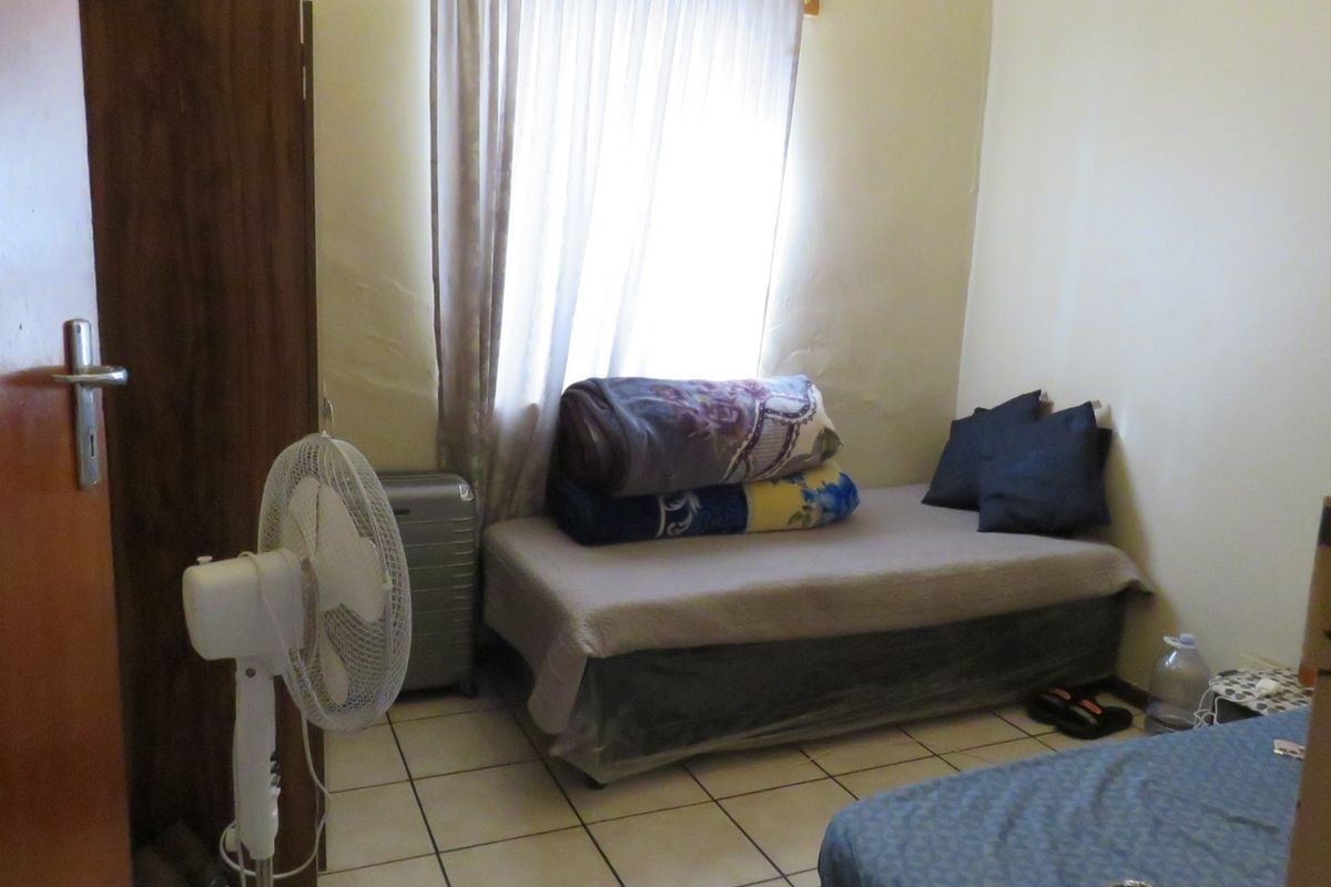 A compact bedroom featuring tiled flooring and a window with curtain rails, requiring cosmetic updates to improve the overall finish.