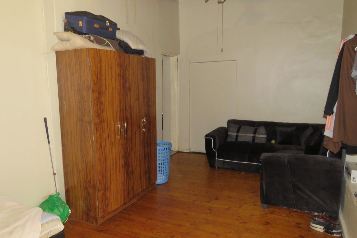 A living area featuring timber flooring and a ceiling fan, requiring cosmetic updates to the wall finishes.