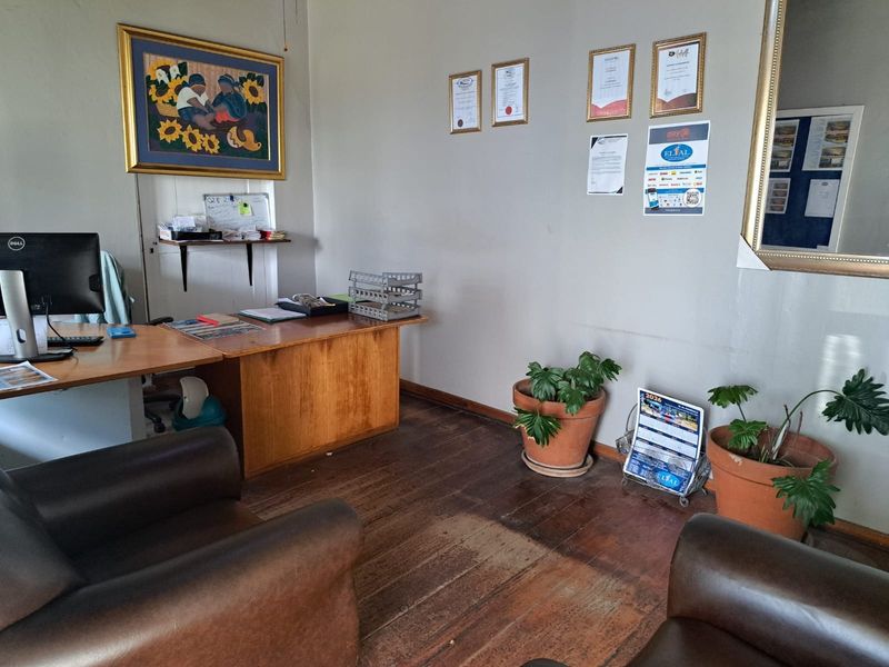A functional office space featuring original timber flooring and a built-in wall shelf, suitable for a professional business environment.