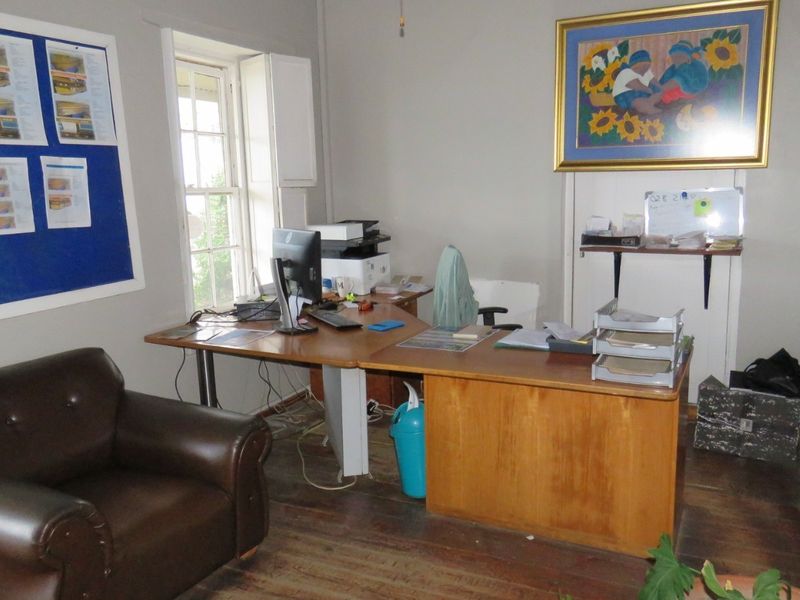 A functional office space featuring original timber flooring and a classic sash window, providing a practical workspace environment.