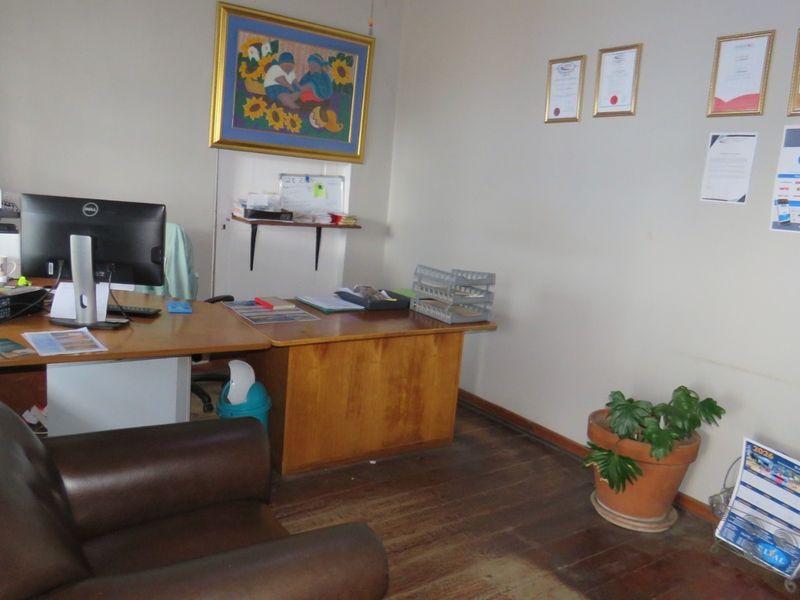 A functional office space featuring original timber flooring and neutral wall finishes, suitable for a professional workspace environment.