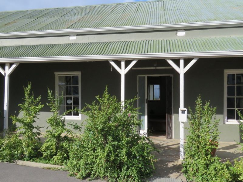 Front facade of a commercial property featuring a covered veranda, corrugated iron roof, and classic sash windows.