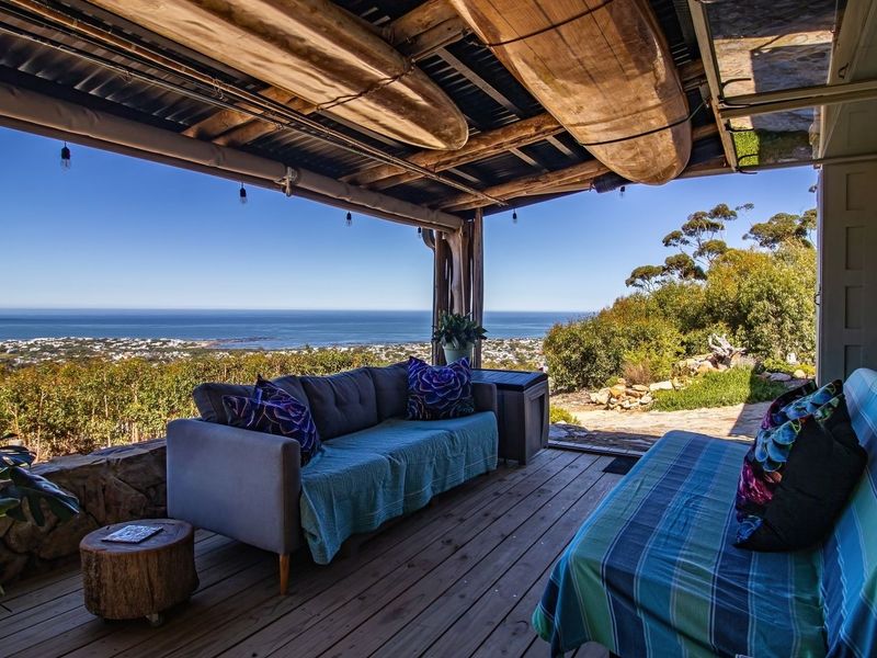 Covered outdoor patio featuring timber decking and exposed beam ceiling, offering expansive coastal and landscape views.