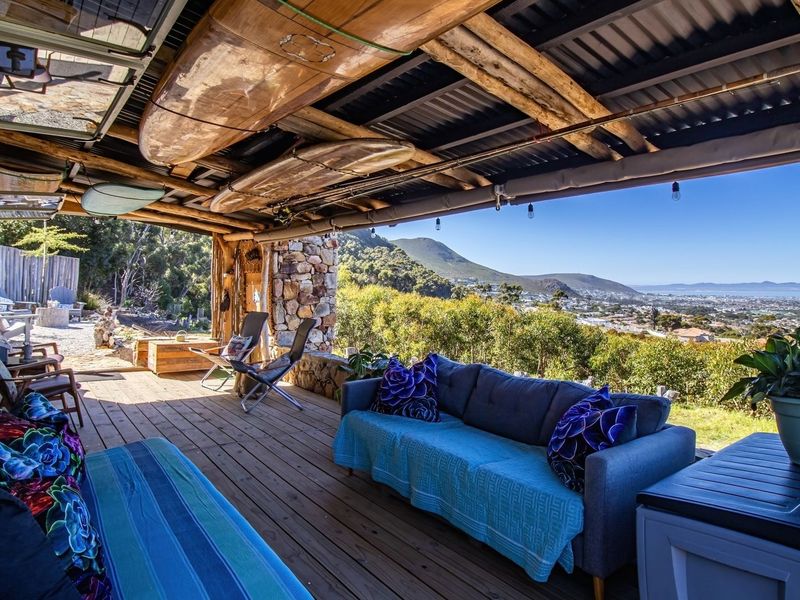 A spacious covered patio featuring timber decking, exposed beam ceiling, and stone masonry, offering expansive scenic views of the surrounding landscape.