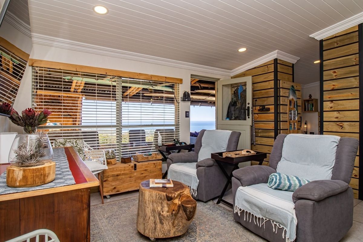 A cozy living area featuring timber wall cladding, tongue and groove ceiling, and large windows providing natural light and scenic views.