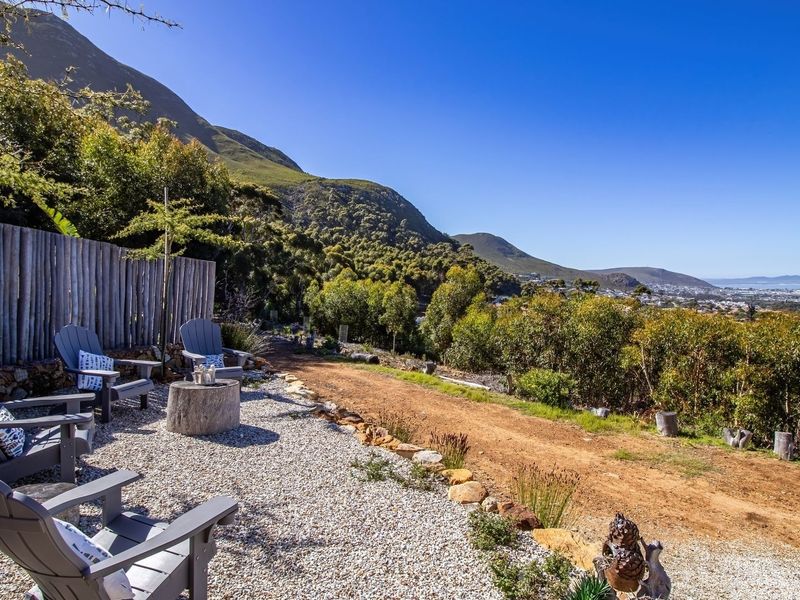 Scenic outdoor gravel seating area featuring timber pole fencing and expansive mountain and coastal landscape views.