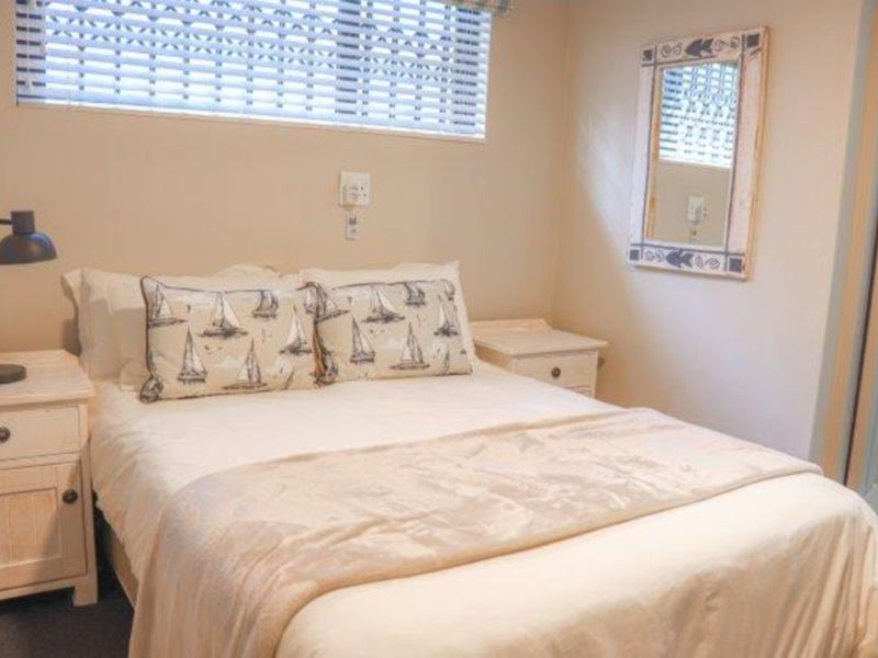 A cozy bedroom featuring neutral walls, venetian blinds, and direct access to an adjoining bathroom.
