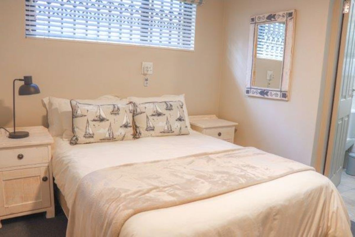 A cozy bedroom featuring neutral walls, venetian blinds, and direct access to an adjoining bathroom.