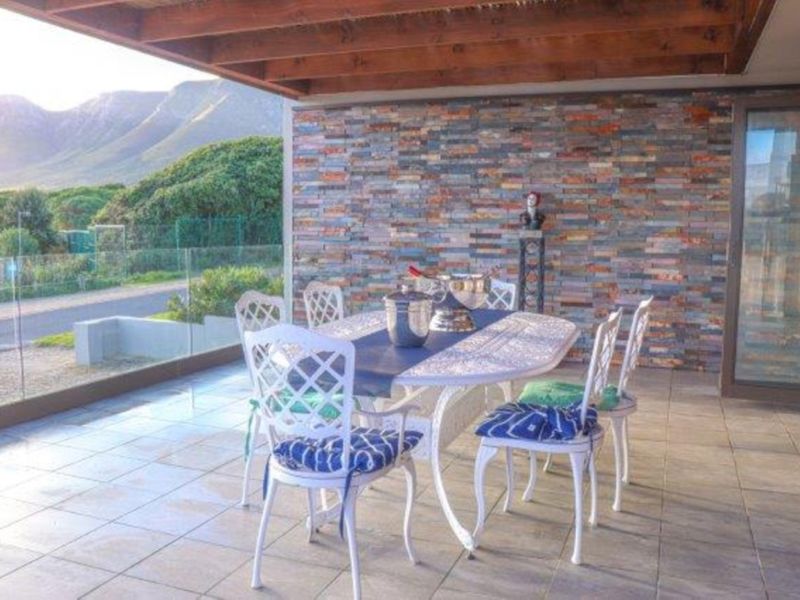 Covered patio featuring a timber pergola, stacked stone feature wall, and glass balustrade with scenic mountain views.