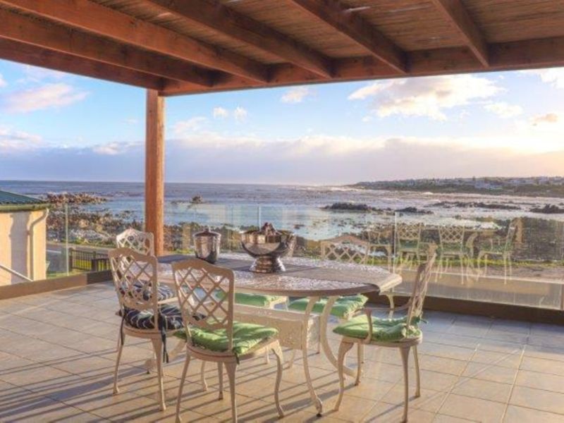 Covered patio featuring a timber pergola, tiled flooring, and a glass balustrade offering expansive ocean views.