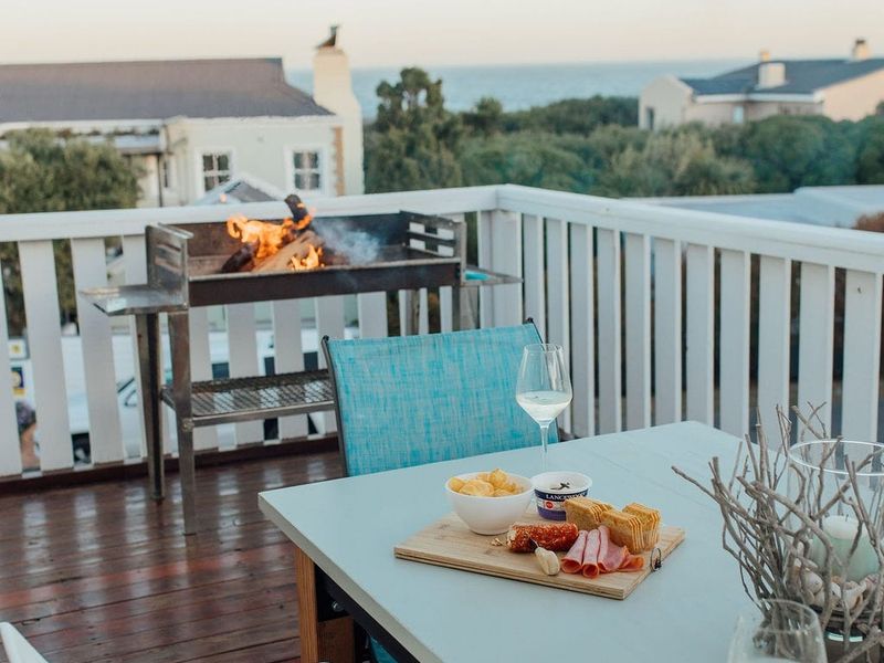 Elevated timber balcony featuring a built-in braai and scenic coastal views, providing an ideal space for outdoor dining and relaxation.