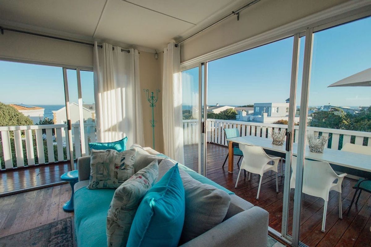 Bright living area featuring expansive sliding glass doors that open onto a wooden deck with coastal views.