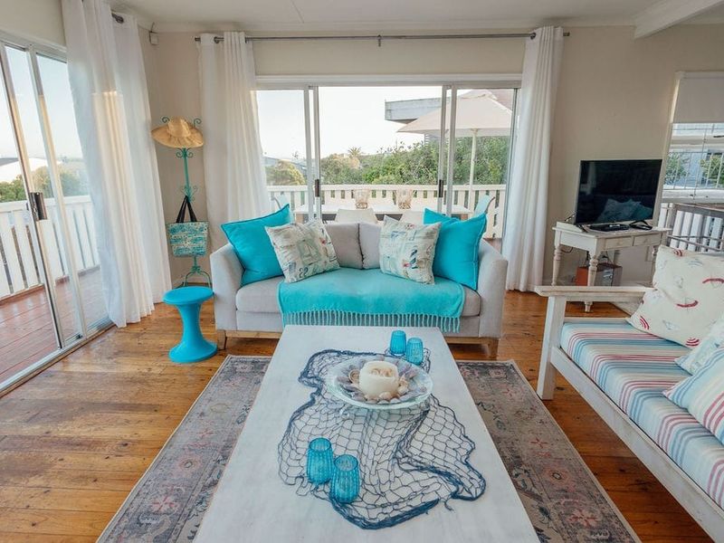 Bright living room featuring warm hardwood flooring and large sliding glass doors that open onto an outdoor balcony area.