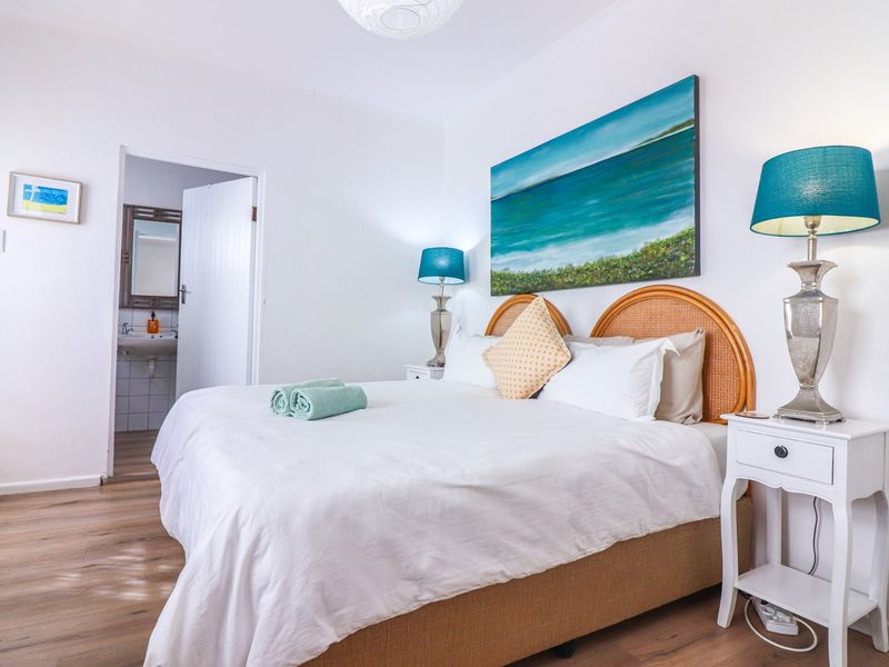 A bright and well-maintained bedroom featuring laminate flooring and direct access to an en-suite bathroom.