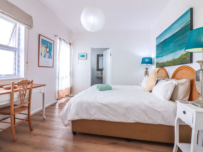 A bright and well-maintained bedroom featuring laminate flooring, a large casement window, and an en-suite bathroom access.
