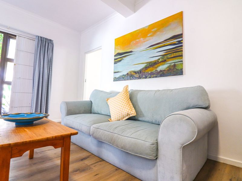 A bright living room featuring laminate flooring and a sliding glass door providing access to the outdoor area.