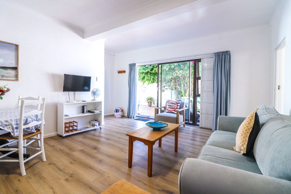 Bright living room featuring laminate flooring and large sliding glass doors providing direct access to the outdoor patio area.