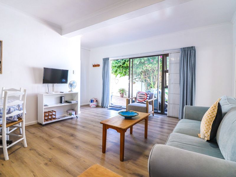 Bright living room featuring laminate flooring and large sliding glass doors providing direct access to the outdoor patio area.