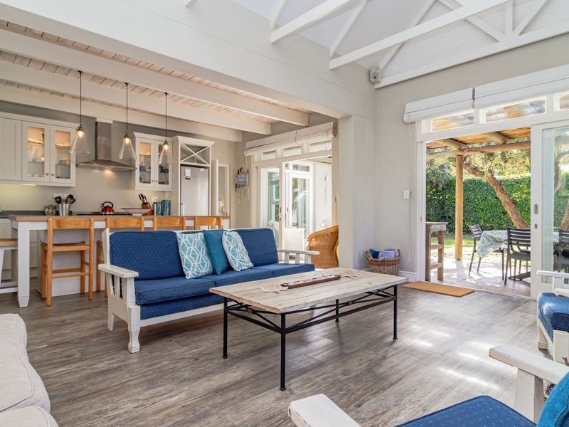 Bright open-plan living area featuring exposed timber ceiling beams, a modern kitchen with breakfast bar, and seamless access to the outdoor patio.