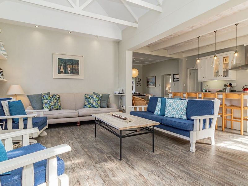 Spacious open-plan living area featuring a vaulted ceiling with exposed beams, a wood-burning fireplace, and a modern kitchen with a central island.