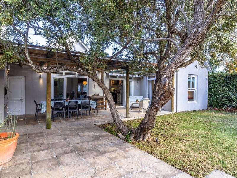 A covered outdoor patio area featuring tiled flooring, a timber pergola, and direct access to the home through sliding glass doors.