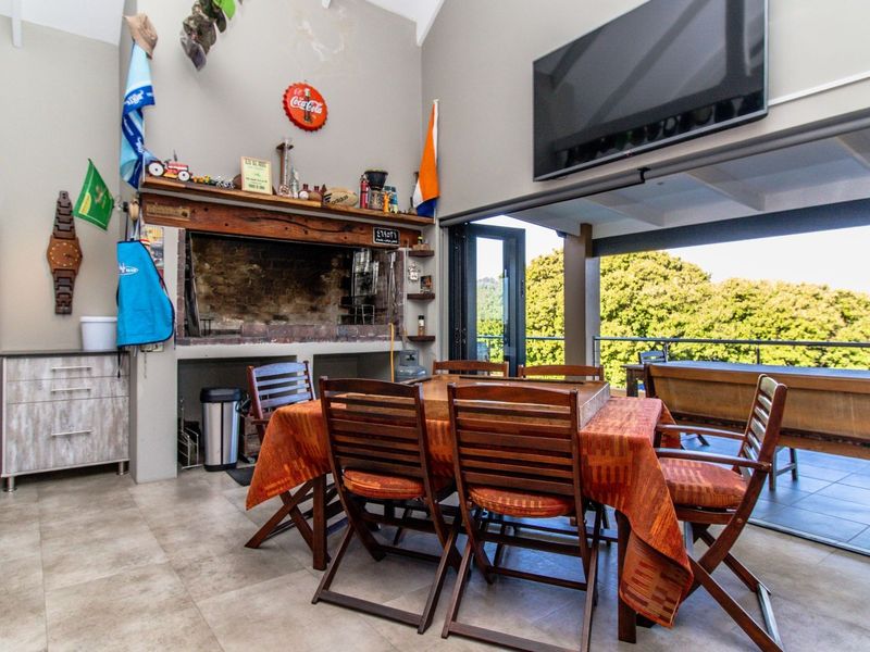 Covered patio area featuring a built-in braai, tiled flooring, and large stacking doors that open to an outdoor view.
